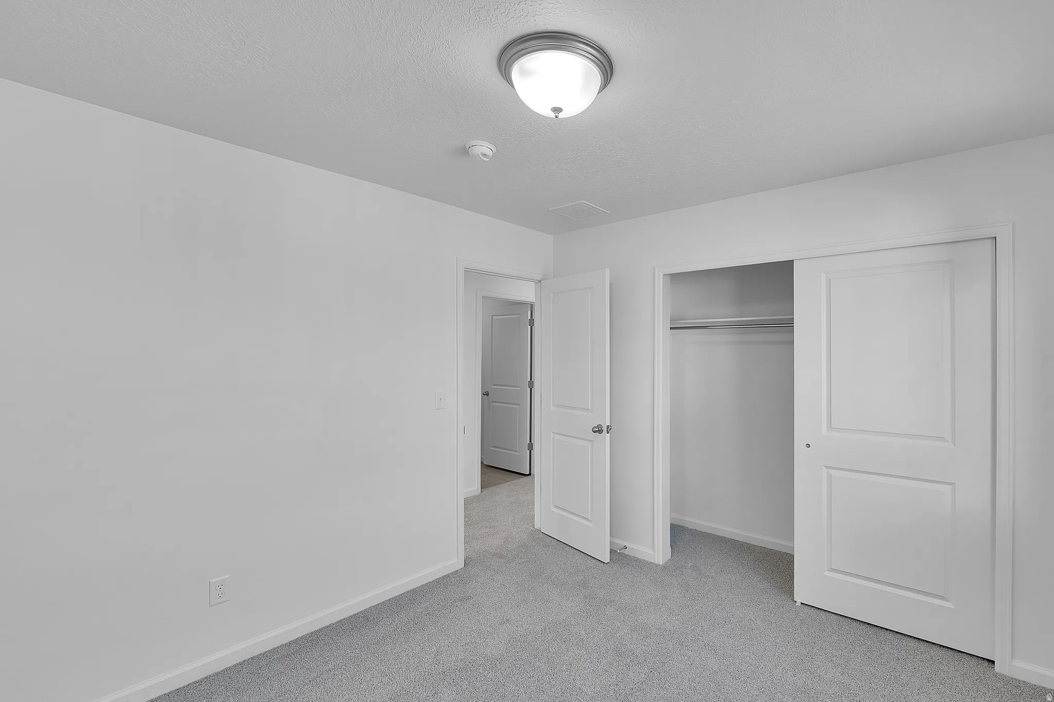 Unfurnished bedroom featuring light carpet and a closet