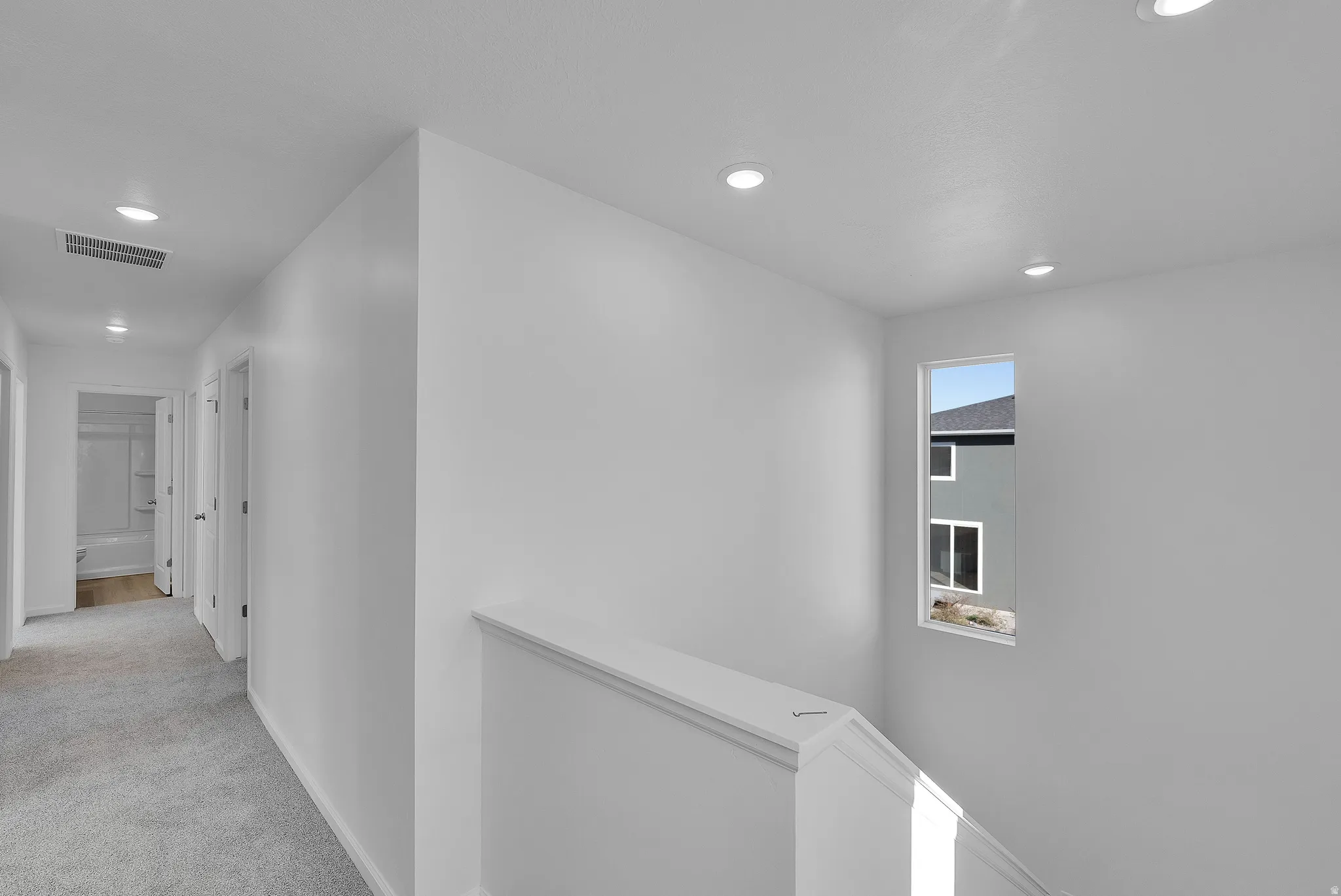 Hall featuring an upstairs landing, light carpet, and recessed lighting