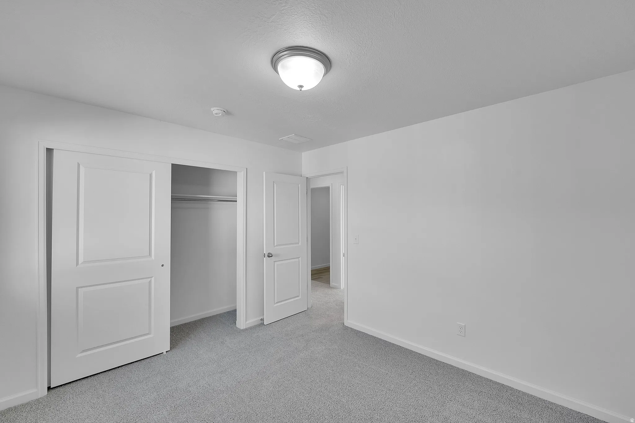 Unfurnished bedroom with light colored carpet and a closet
