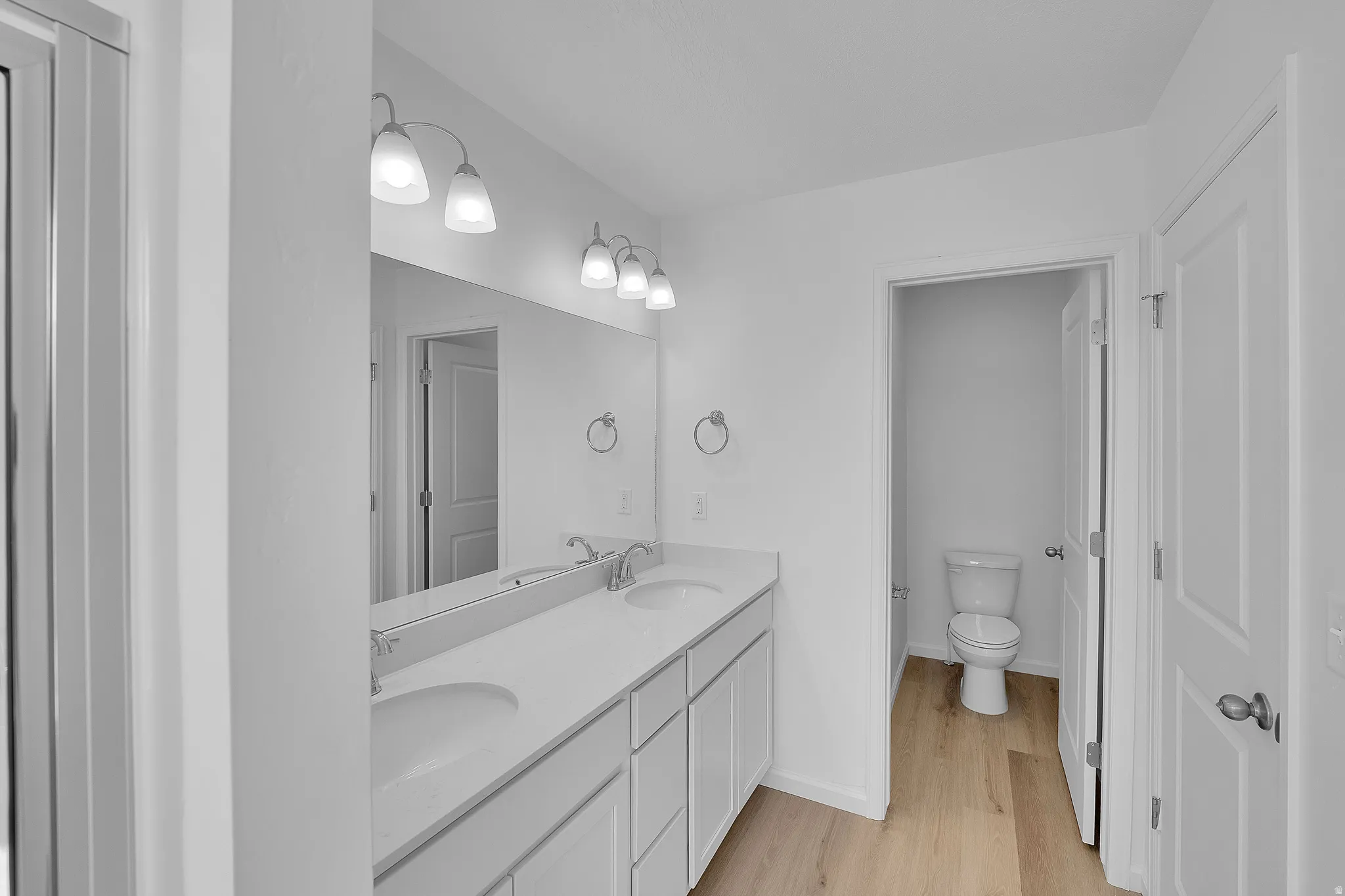 Full bathroom featuring double vanity and light wood finished floors