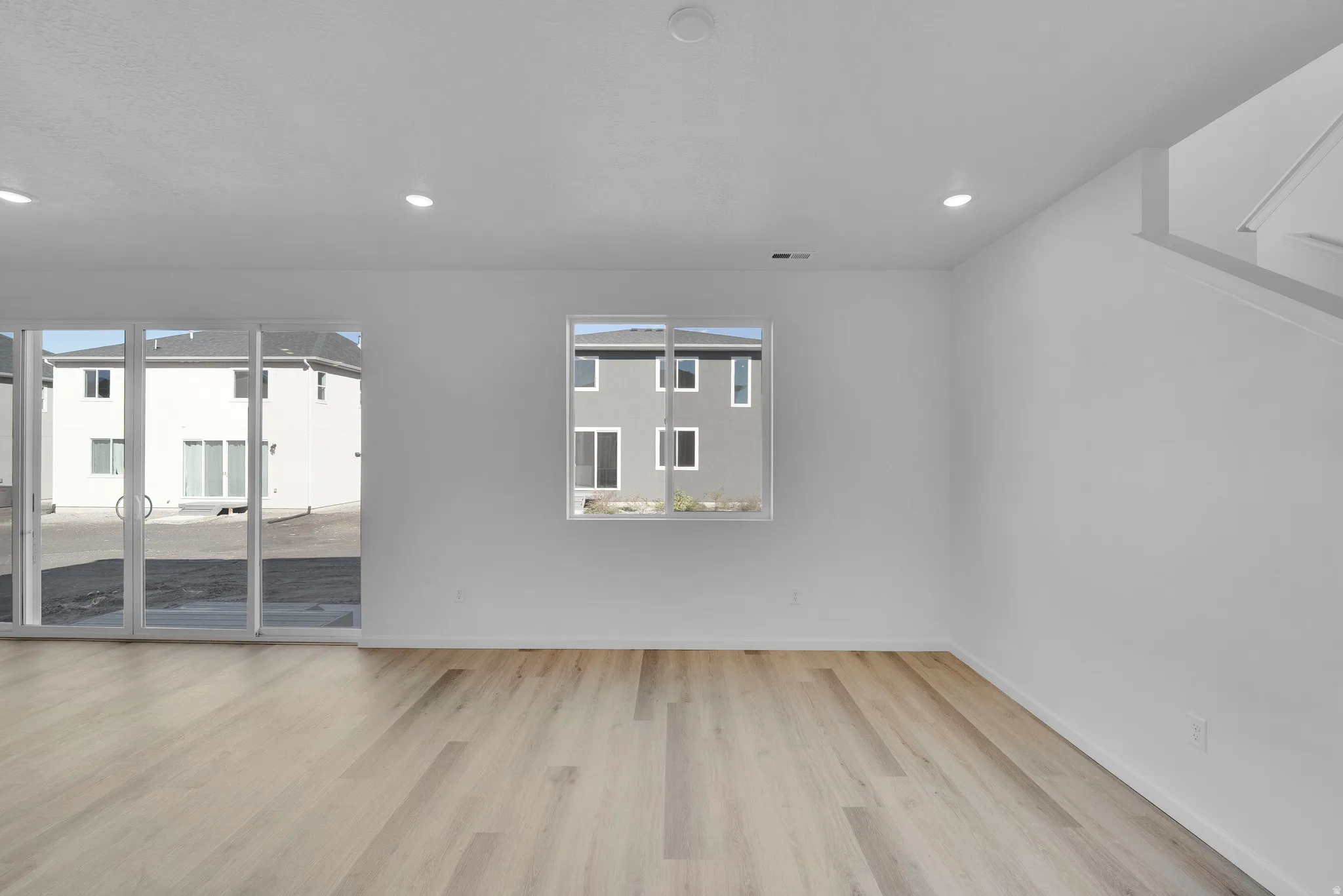 Empty room with light wood finished floors and recessed lighting