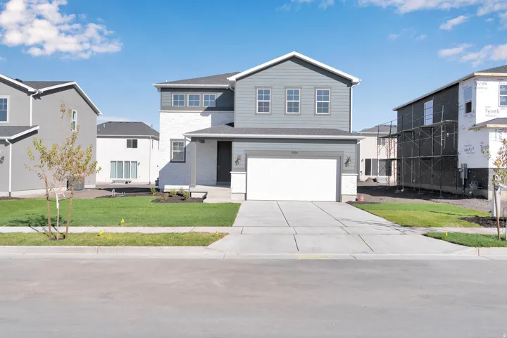 Traditional-style home featuring a garage, a front lawn, and concrete driveway