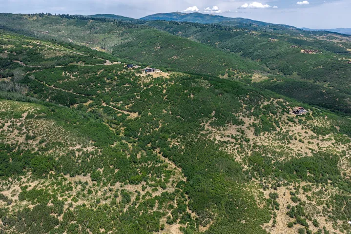 Expansive mountain landscape featuring varied topography, distant mountain ranges, and scattered residential properties