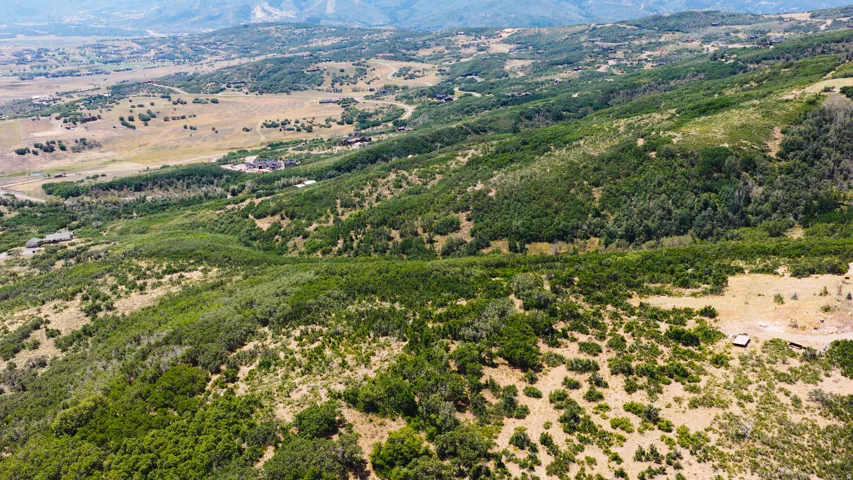 Expansive aerial landscape featuring rolling hills, varied terrain, and distant mountain ranges