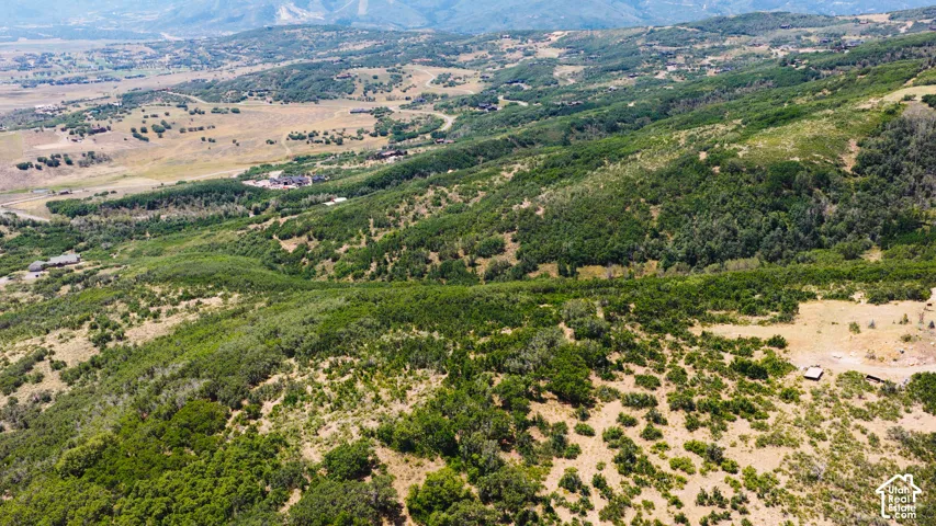 Expansive aerial landscape featuring rolling hills, varied terrain, and distant mountain ranges