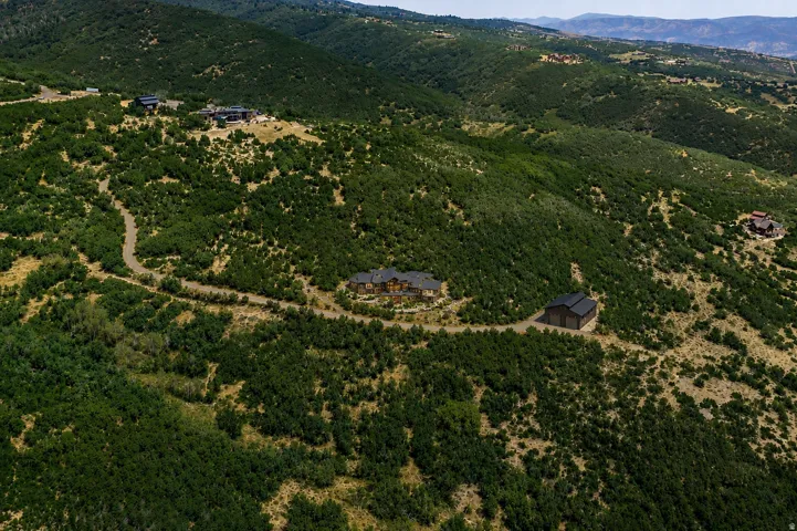 Expansive hillside property featuring a main residence, a secondary building, and a winding driveway