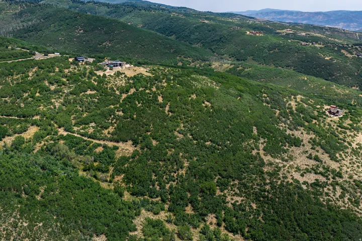 Extensive hillside property featuring a prominent structure with multiple levels, surrounded by substantial natural vegetation