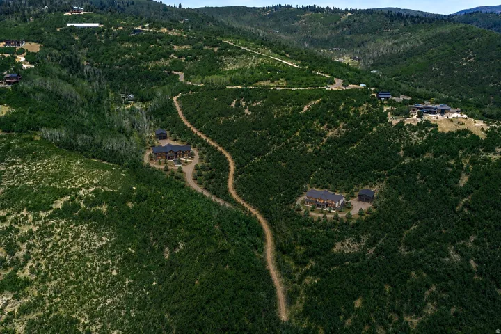 Expansive mountain terrain with winding roads, surrounded by lush green foliage