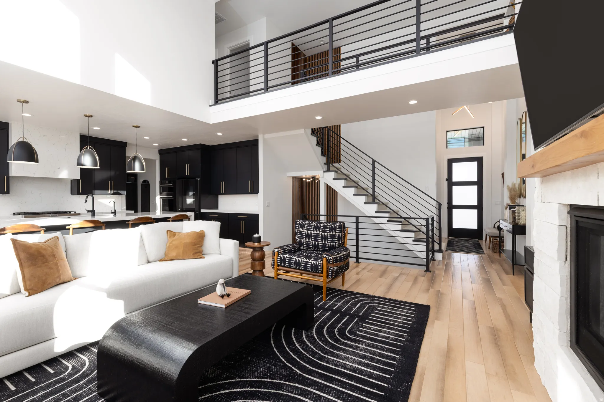 Living room featuring a high ceiling, stairs, recessed lighting, light wood finished floors, and a glass covered fireplace