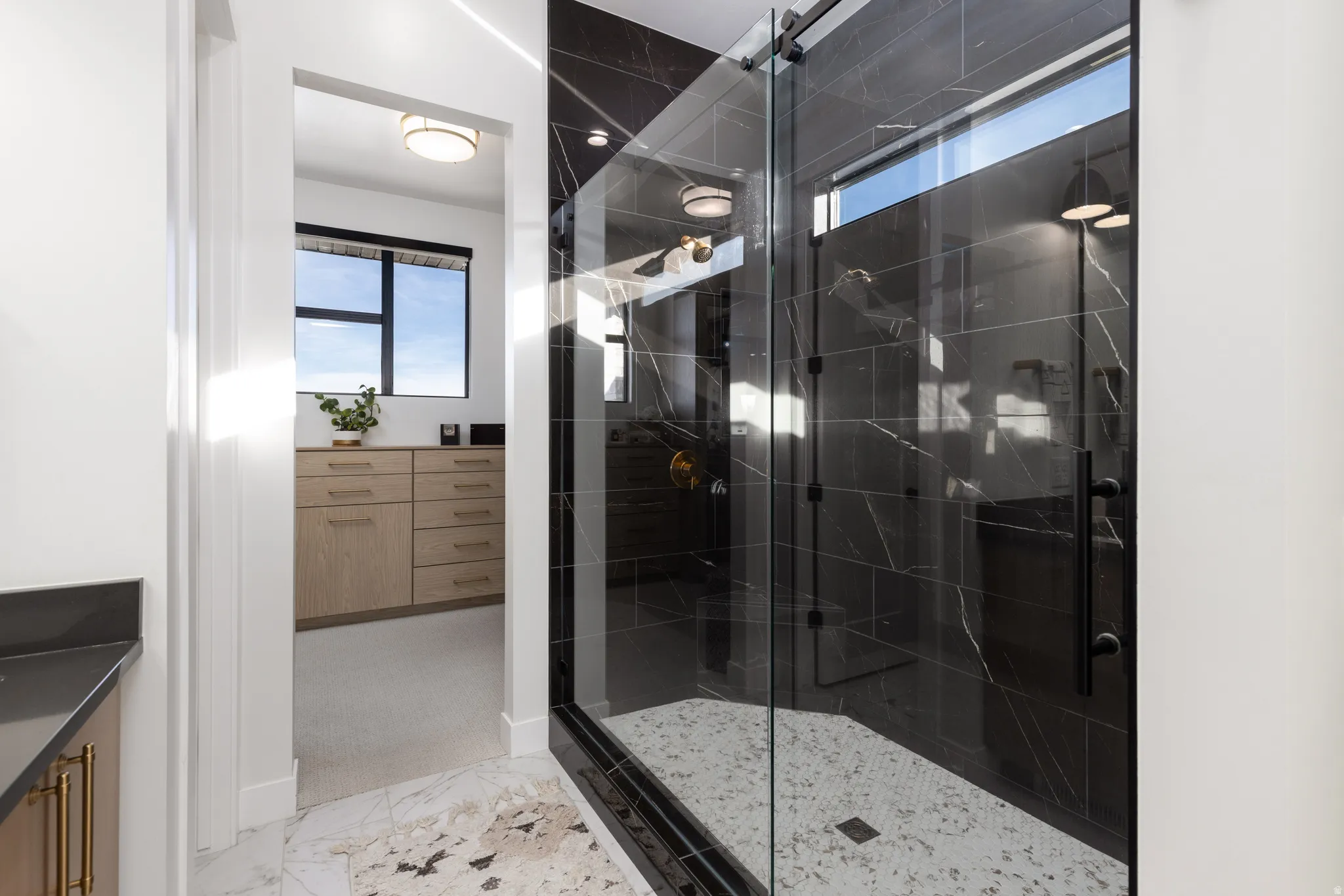 Bathroom featuring vanity, light marble finish flooring, and a marble finish shower