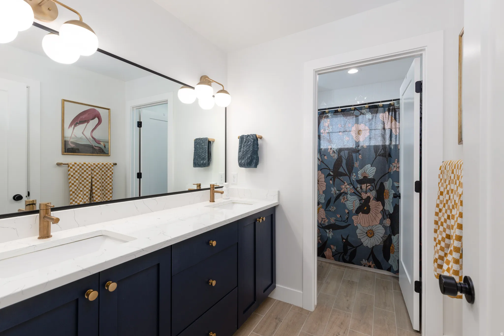 Bathroom with double vanity, a shower with shower curtain, and wood finish floors