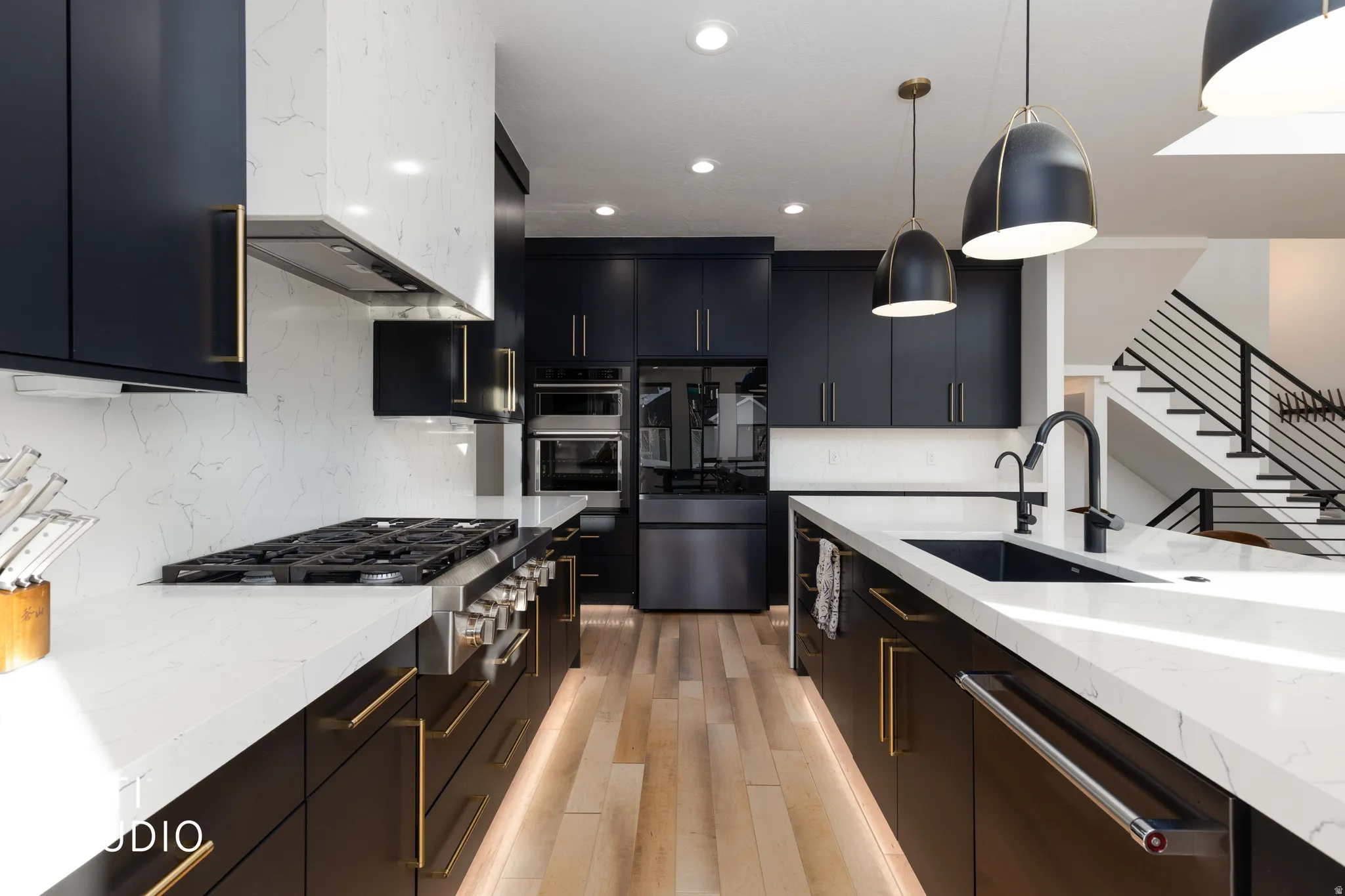 Kitchen with stainless steel appliances, light stone counters, hanging light fixtures, recessed lighting, and light wood-style flooring