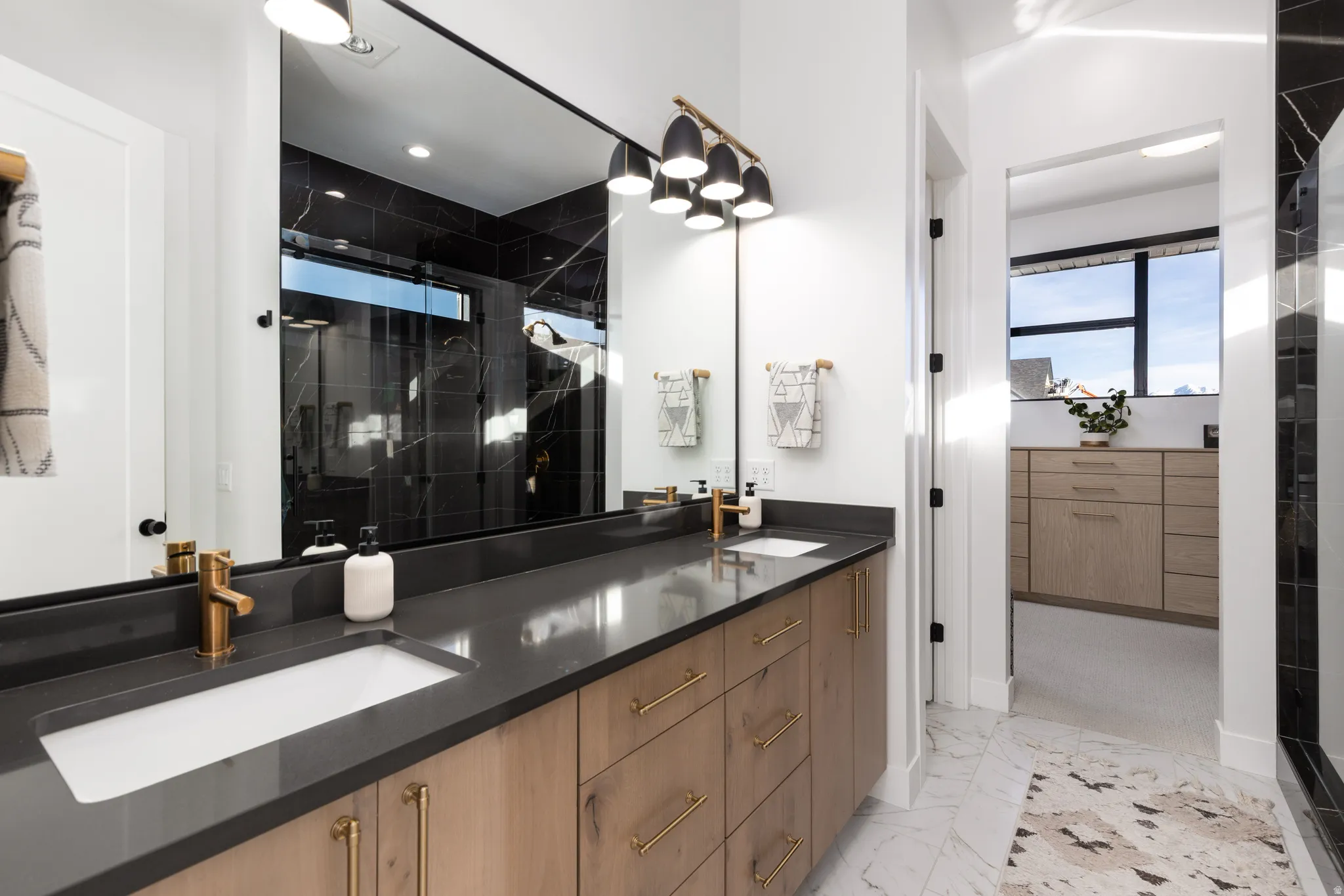 Full bath with a shower stall, light marble finish floors, and double vanity