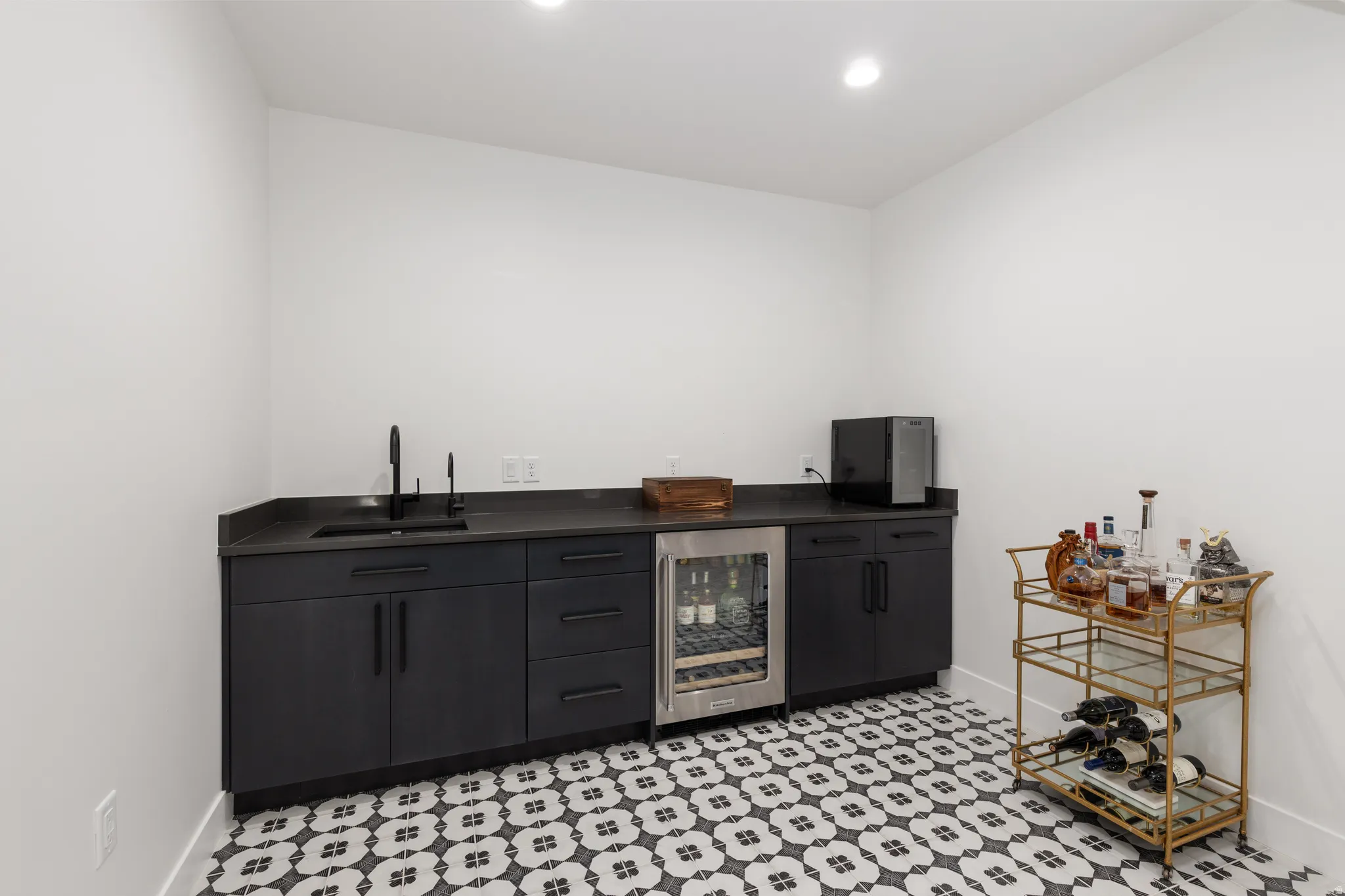 Indoor wet bar featuring beverage cooler, dark countertops, light flooring, dark cabinets, and recessed lighting