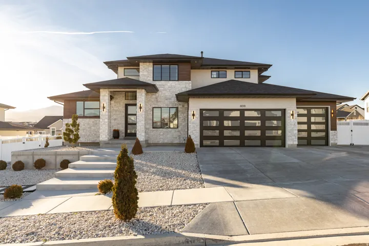 Prairie-style house featuring stone siding, an attached garage, concrete driveway, and a gate