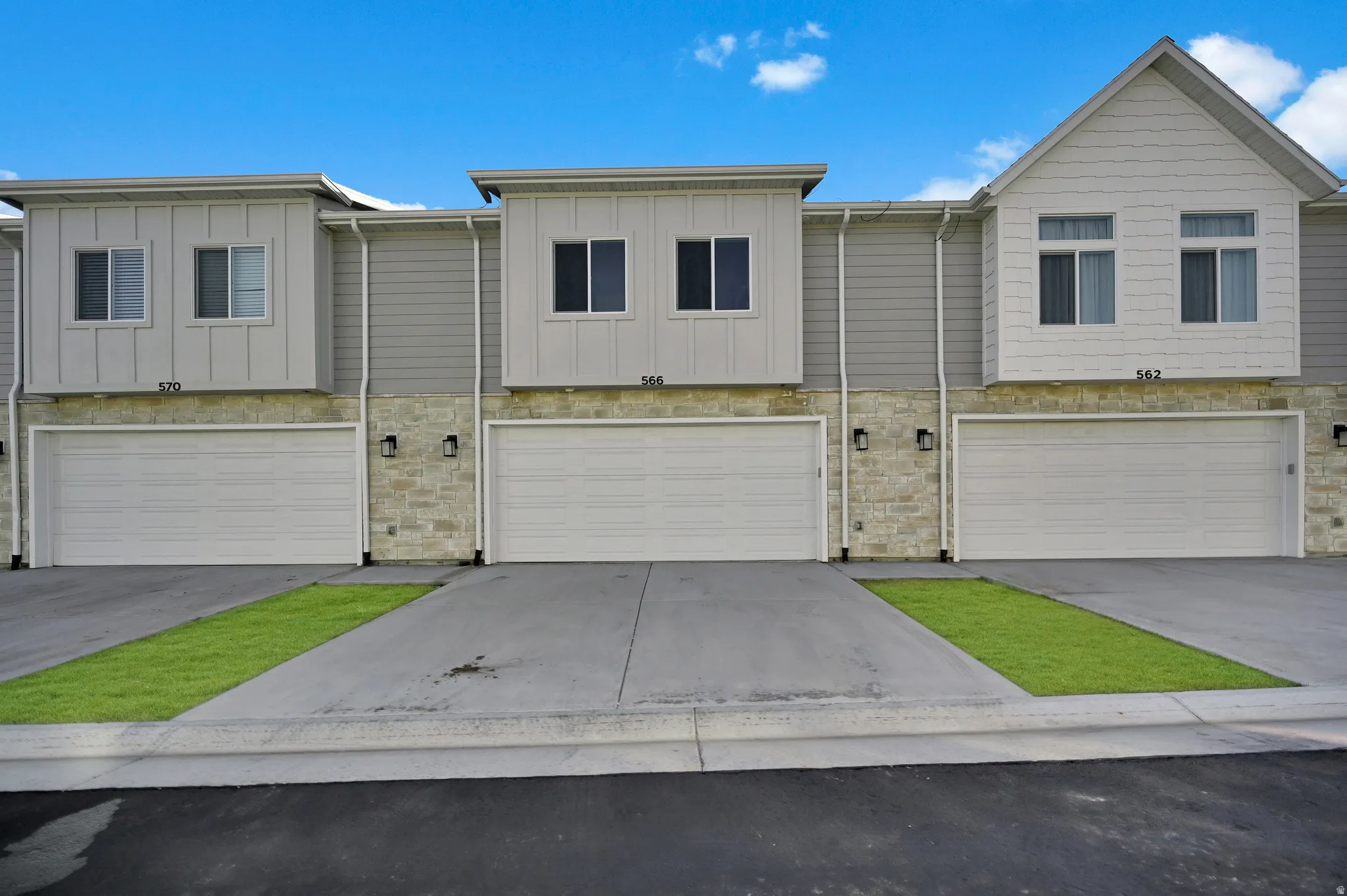 View of front of house featuring stone siding, board and batten siding, an attached garage, and driveway