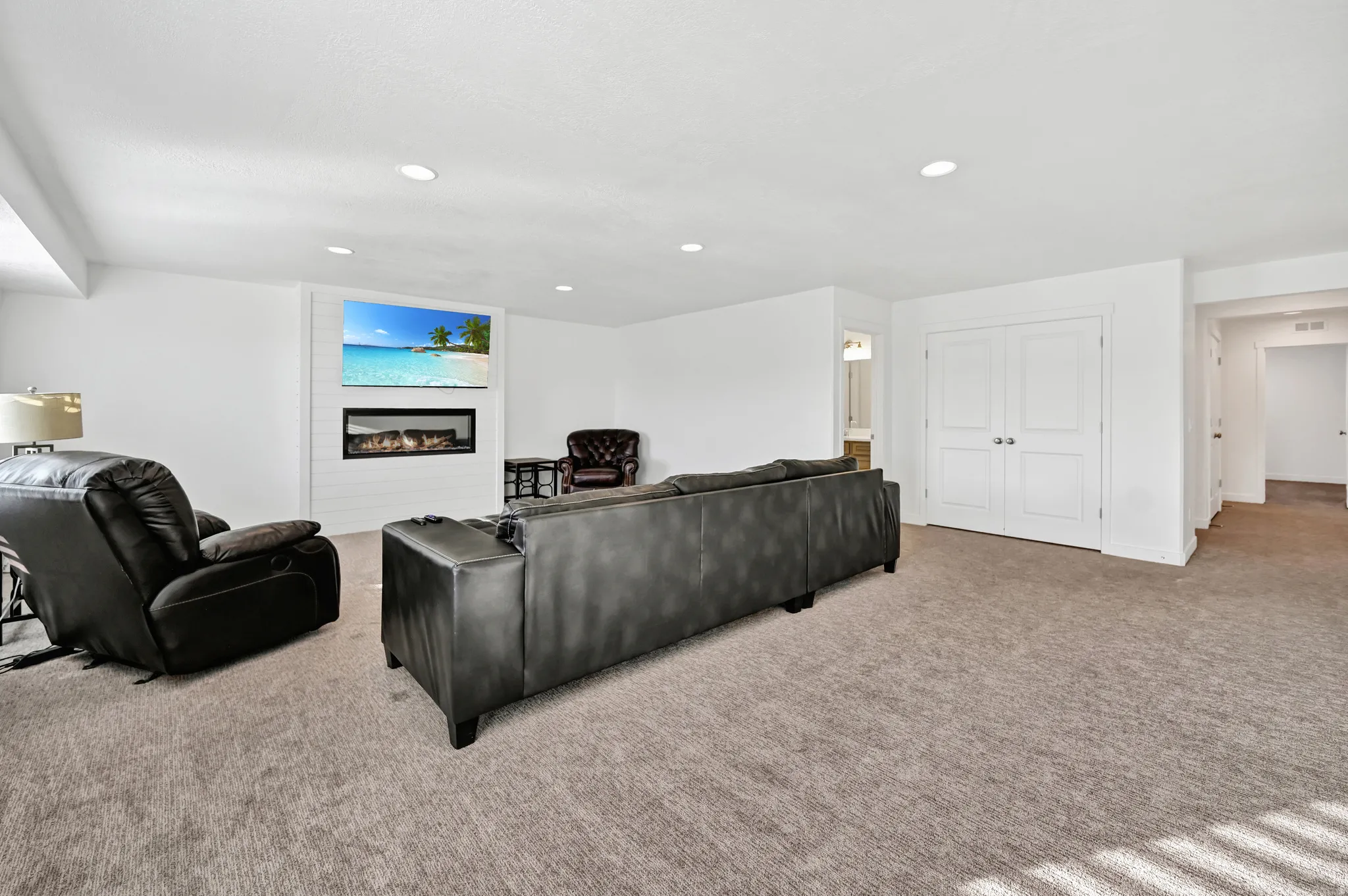 Carpeted living area with a glass covered fireplace and recessed lighting