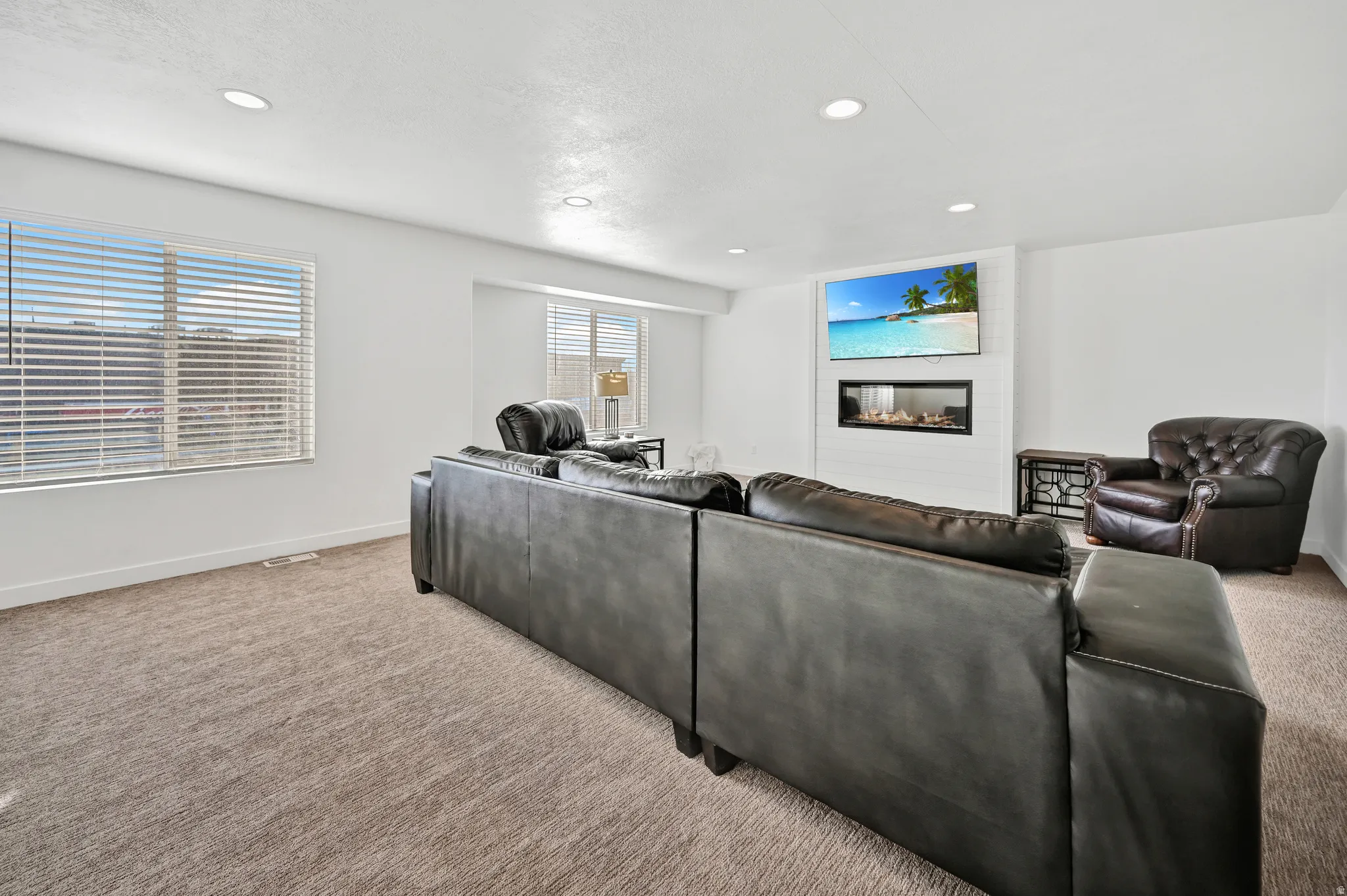 Living area featuring carpet flooring, a glass covered fireplace, and recessed lighting