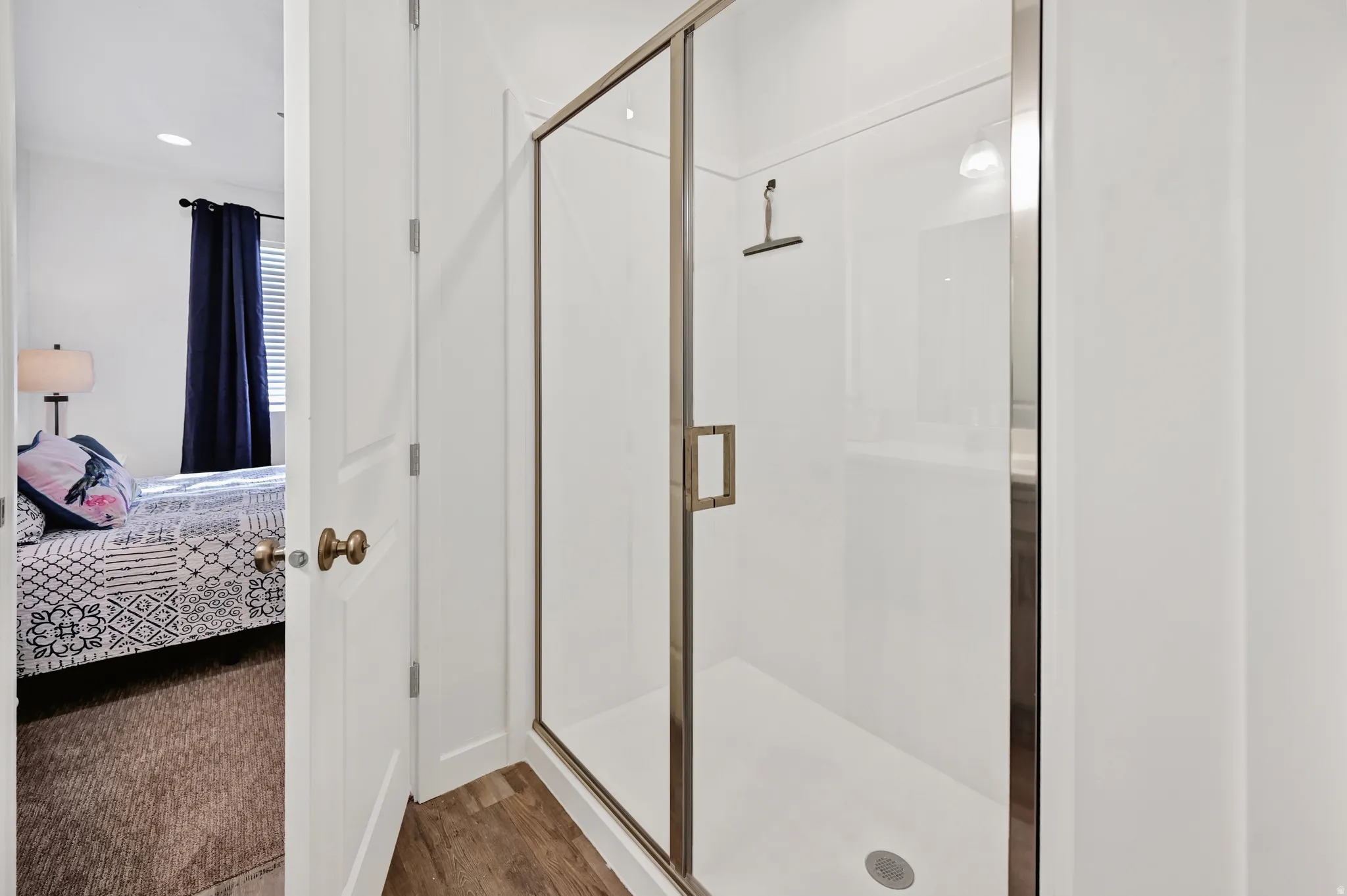 Full bathroom with connected bathroom, a shower stall, and wood finished floors