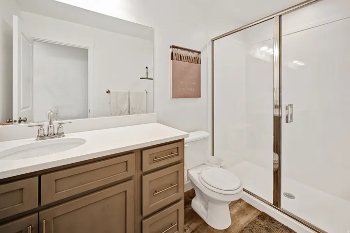 Bathroom featuring a stall shower, vanity, and dark wood-style flooring