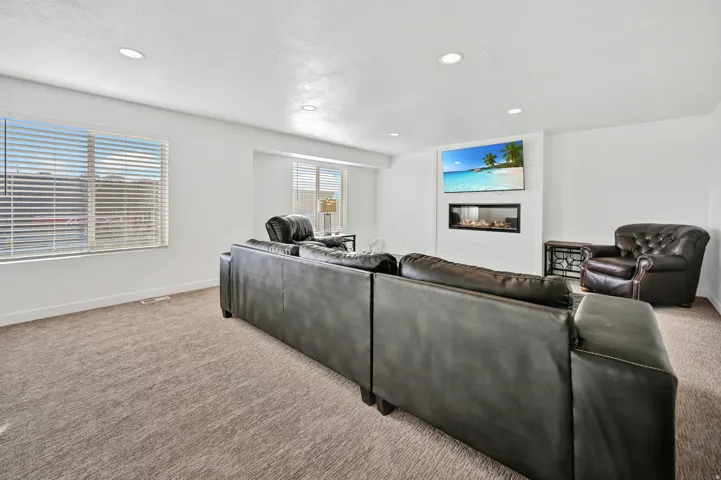 Living area featuring carpet flooring, a glass covered fireplace, and recessed lighting