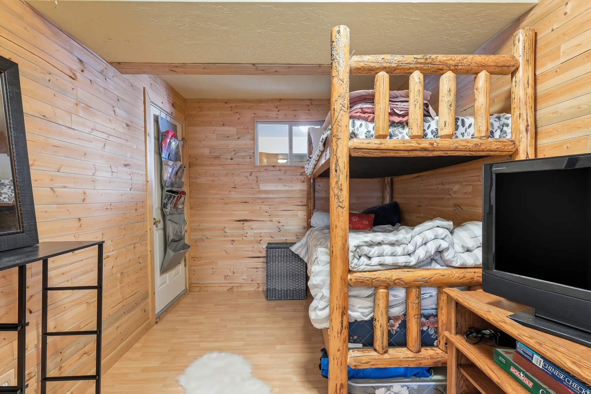 Bedroom featuring wood walls, wood finished floors, and a textured ceiling