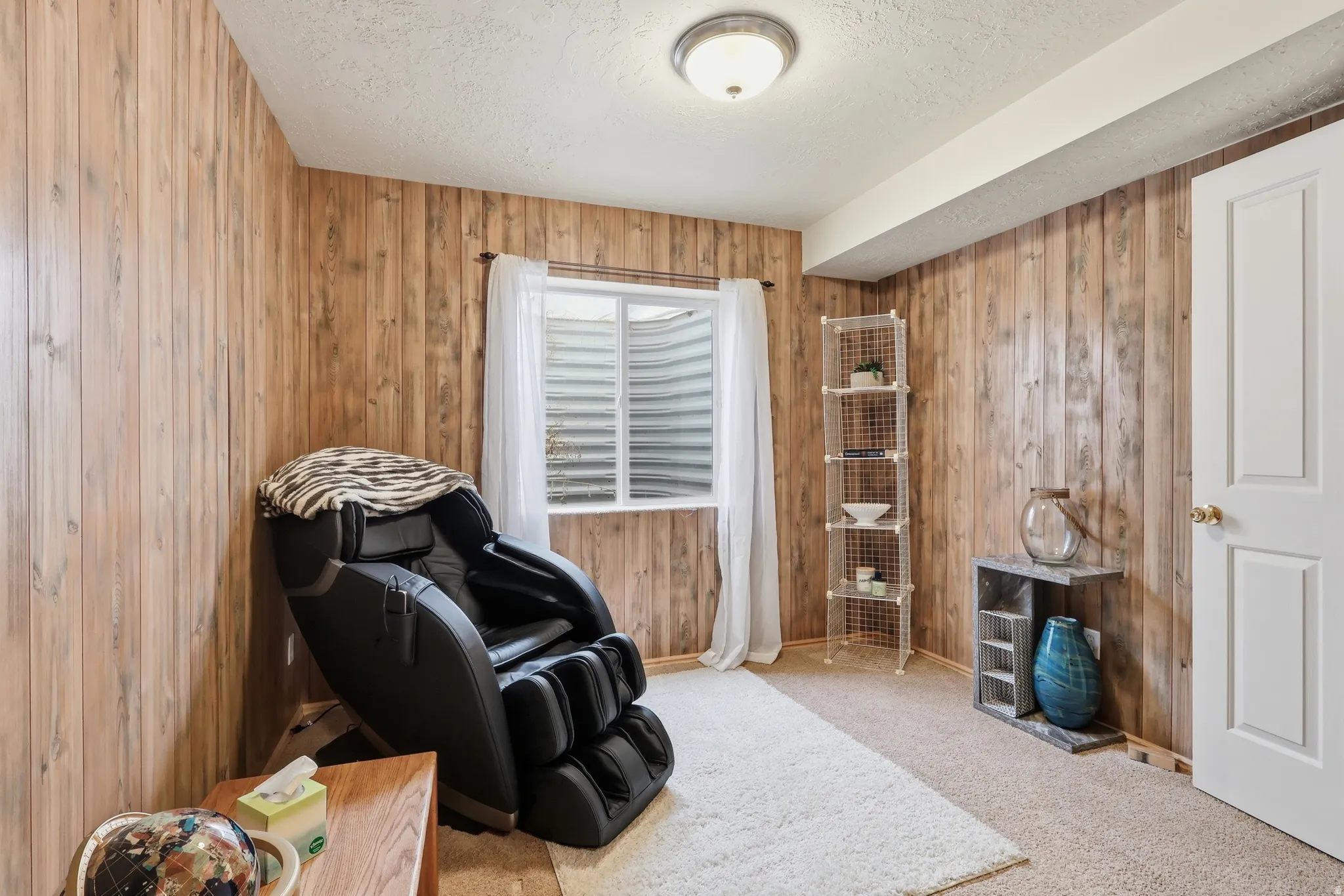 Sitting room featuring carpet, a textured ceiling, and wood walls