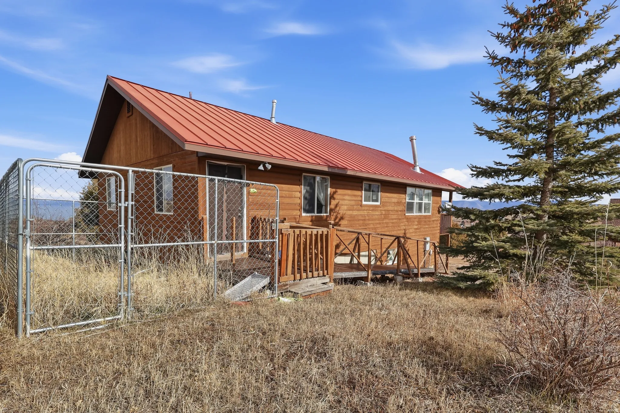Rear view of house featuring a gate and a metal roof