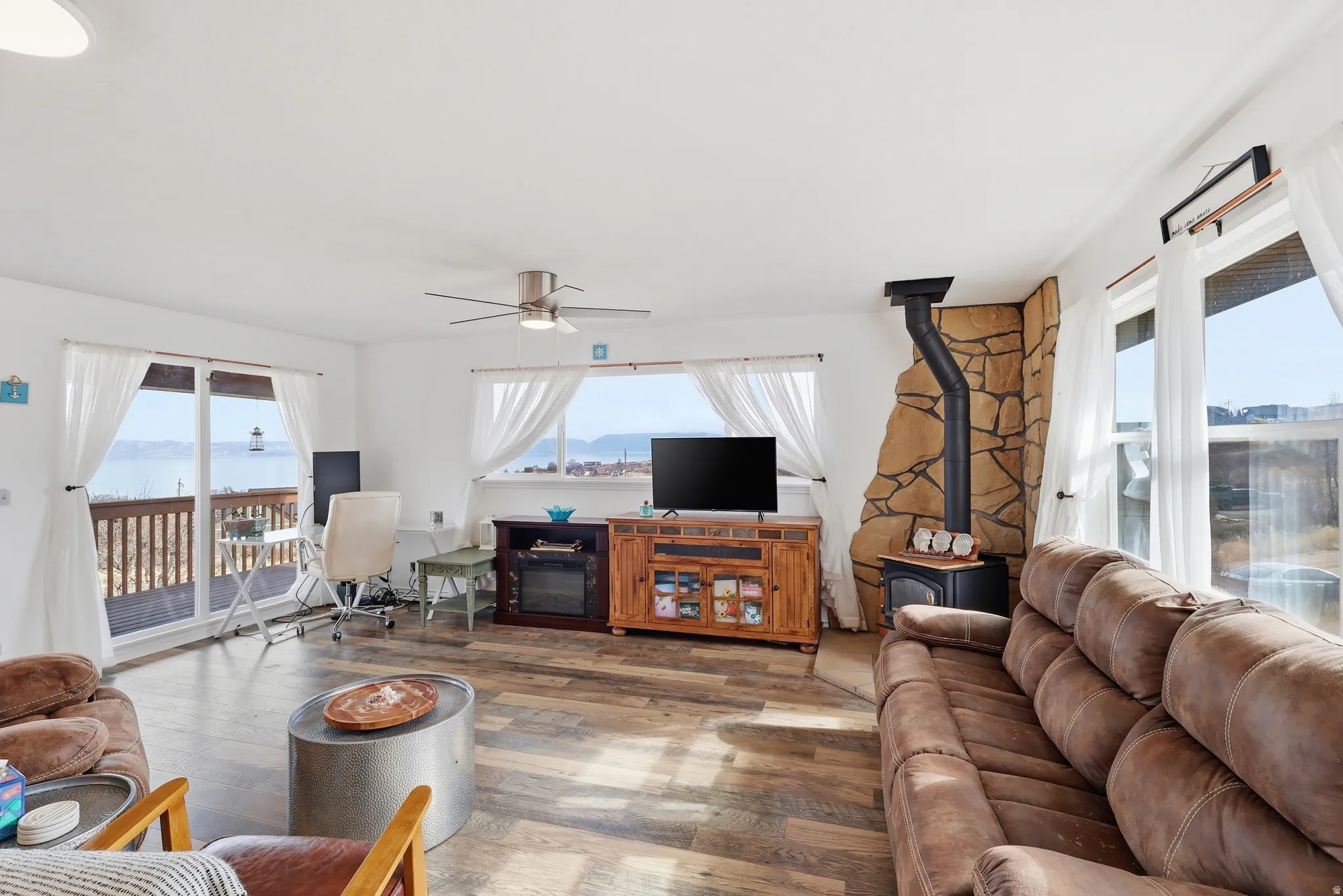 Living room with a wood stove, wood finished floors, and a ceiling fan