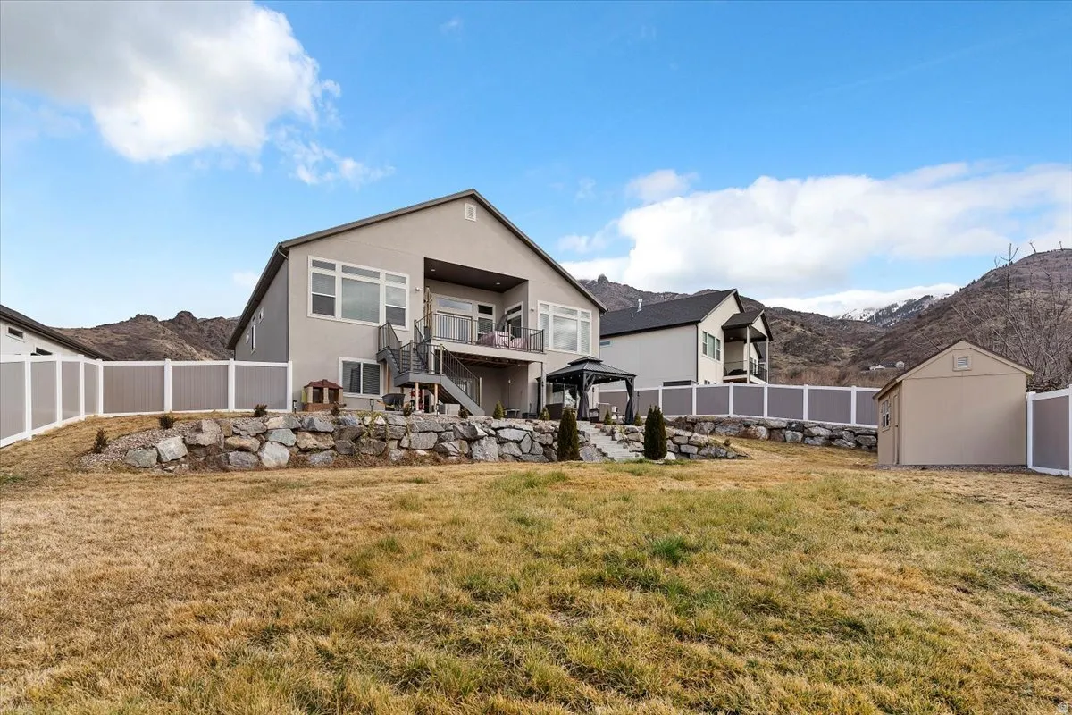 Rear view of property with a balcony, stucco siding, a fenced backyard, a shed, and a patio area