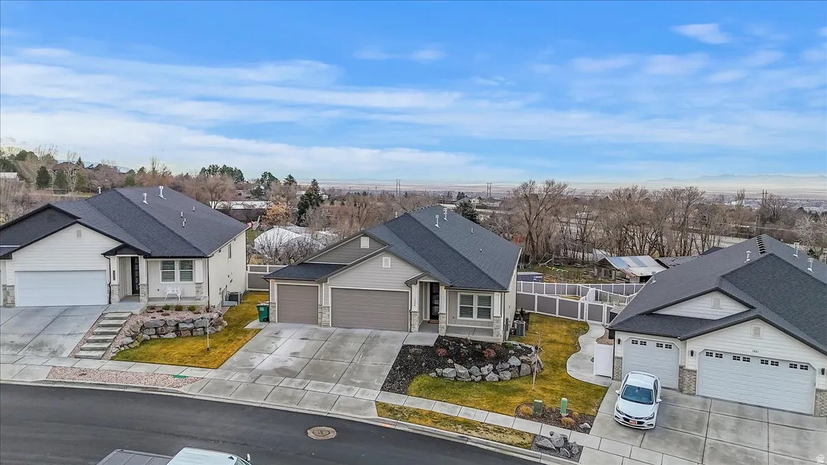 Single story home featuring driveway, an attached garage, a residential view, and roof with shingles