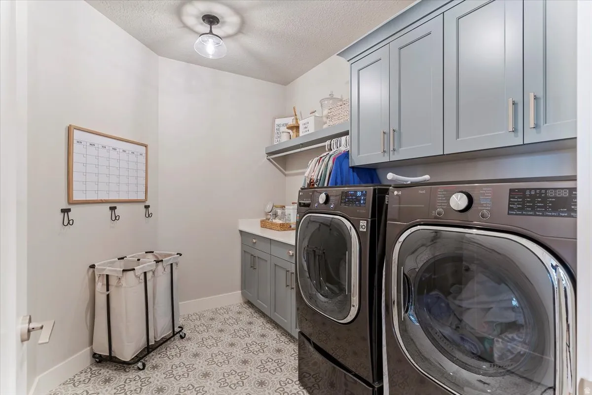 Laundry area with cabinet space, a textured ceiling, and independent washer and dryer
