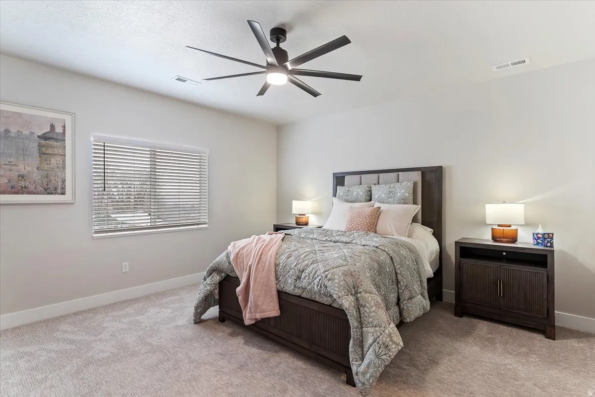 Carpeted bedroom featuring a ceiling fan and baseboards