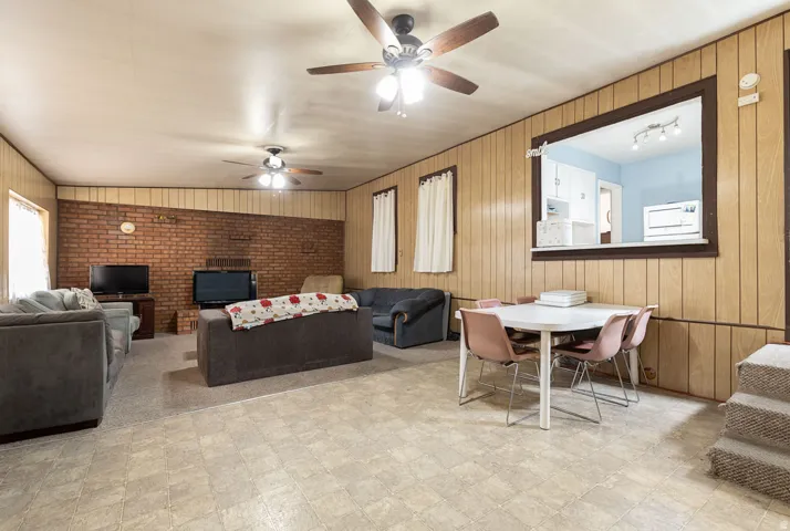 Living area featuring wood walls, tile patterned floors, and ceiling fan