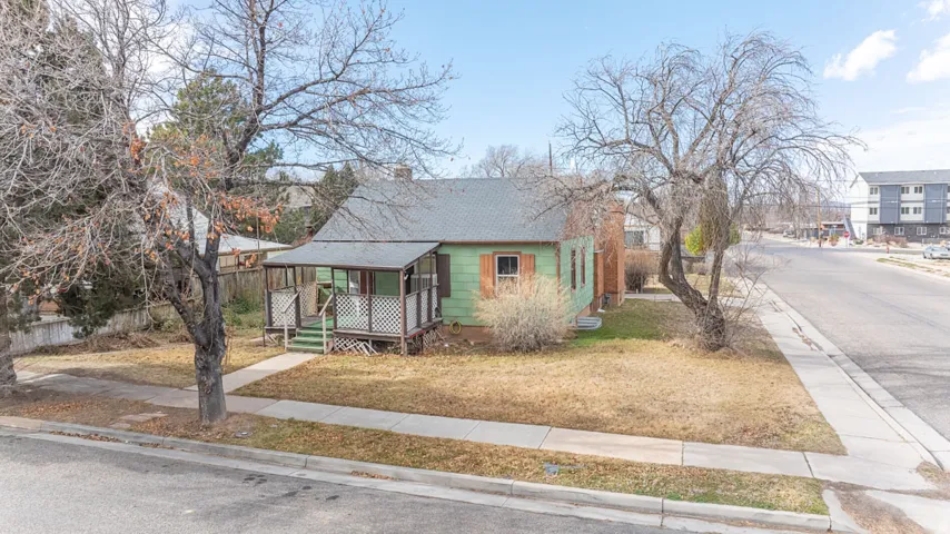 View of front of house featuring roof with shingles, covered porch, and a front yard