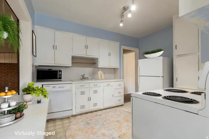 Kitchen with white appliances, light floors, white cabinetry, and light countertops