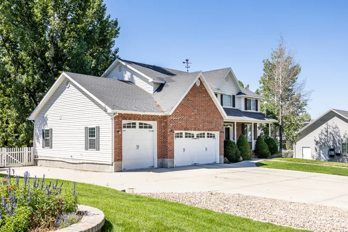 View of front of home with concrete driveway, a garage, a porch, brick siding, and a shingled roof