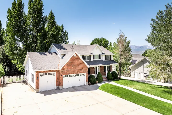Traditional-style home featuring driveway, a porch, an attached garage, brick siding, and a shingled roof