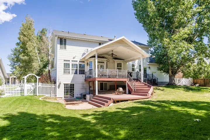 Back of property with a gate, a patio area, a fenced backyard, a ceiling fan, and a deck