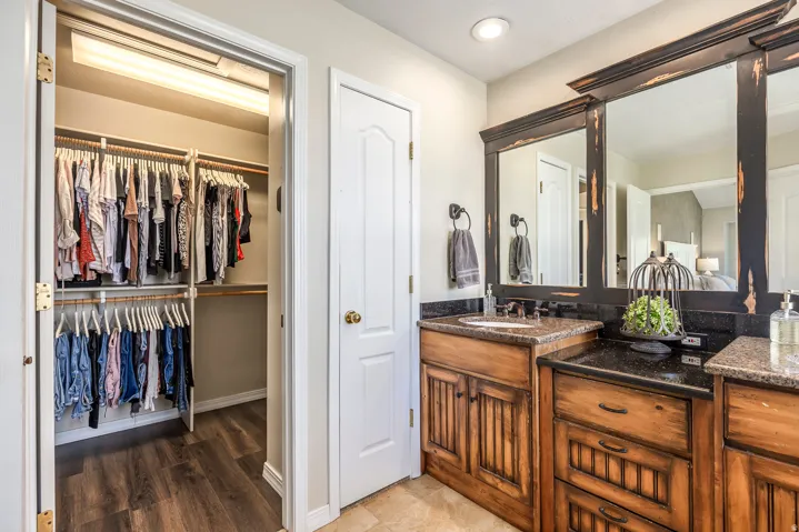 Full bath with vanity, a spacious closet, and light wood-type flooring
