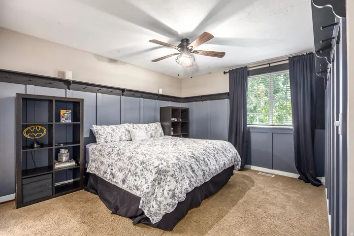 Bedroom featuring light carpet, a ceiling fan, and a decorative wall