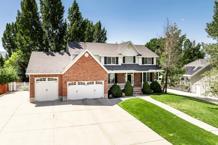 Traditional-style house with covered porch, brick siding, a garage, and driveway