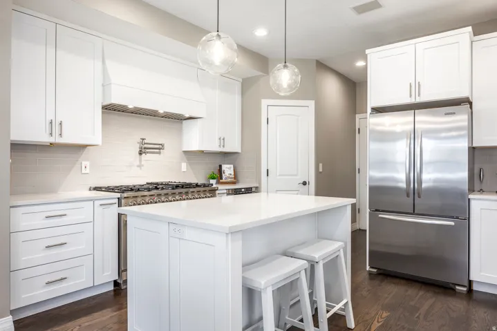 Kitchen with freestanding refrigerator, white cabinets, and a kitchen breakfast bar