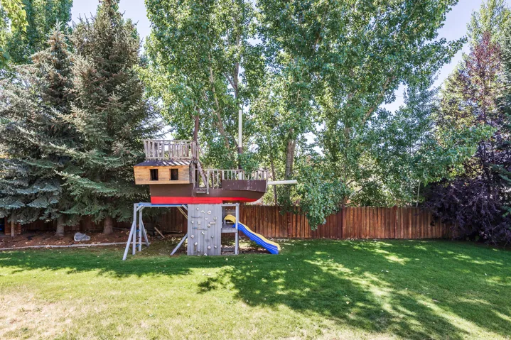 Fenced backyard featuring a playground