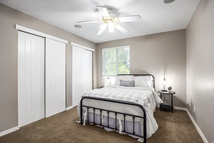 Bedroom with two closets, a ceiling fan, dark carpet, and a textured ceiling