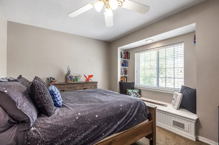 Carpeted bedroom featuring ceiling fan