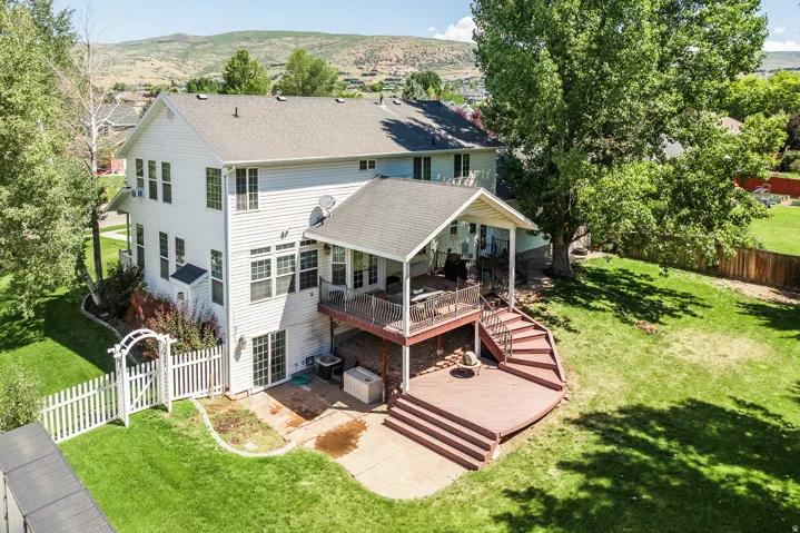 Rear view of property featuring a patio, roof with shingles, a fenced backyard, and a deck with mountain view