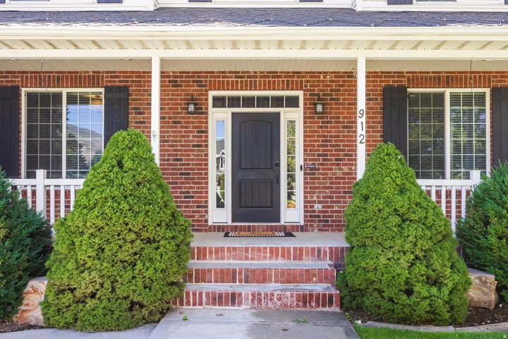 Entrance to property with a porch and brick siding