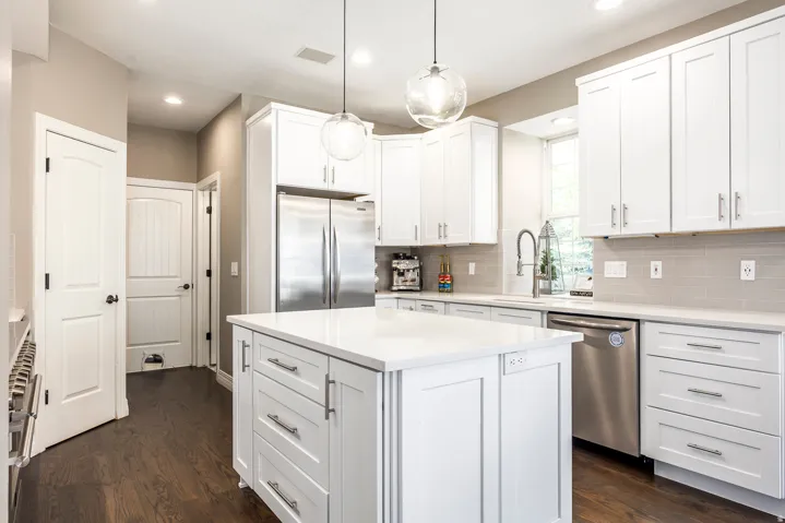 Kitchen featuring stainless steel appliances, white cabinets, hanging light fixtures, and a kitchen island