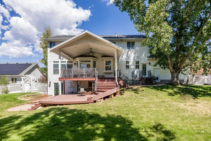 Rear view of house with a wooden deck, a fenced backyard, a ceiling fan, and a gate